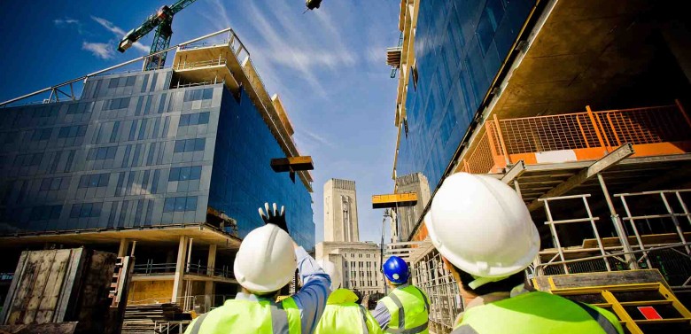 Construction workers and real estate investors look at commercial buildings being built.